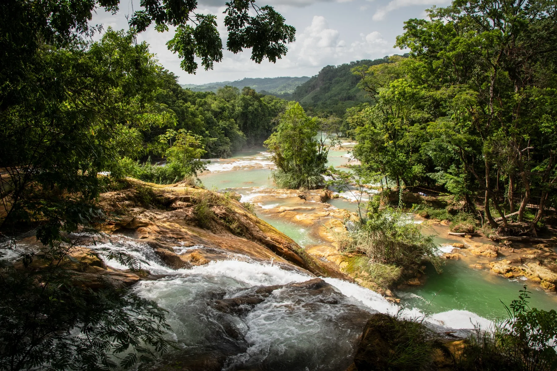 Waterfalls and a turquoise river surrounded by forest.