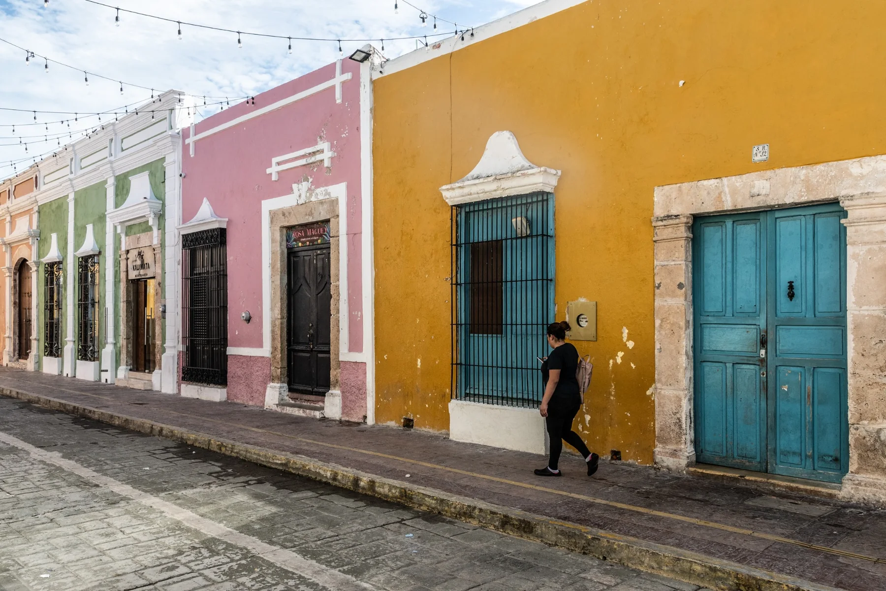 Colourful façades on a Mexican street with a woman walking past.