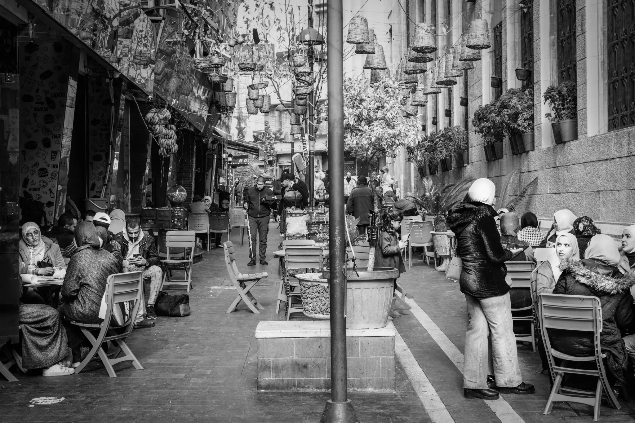 A street in Amman filled with café tables and people sitting outside.