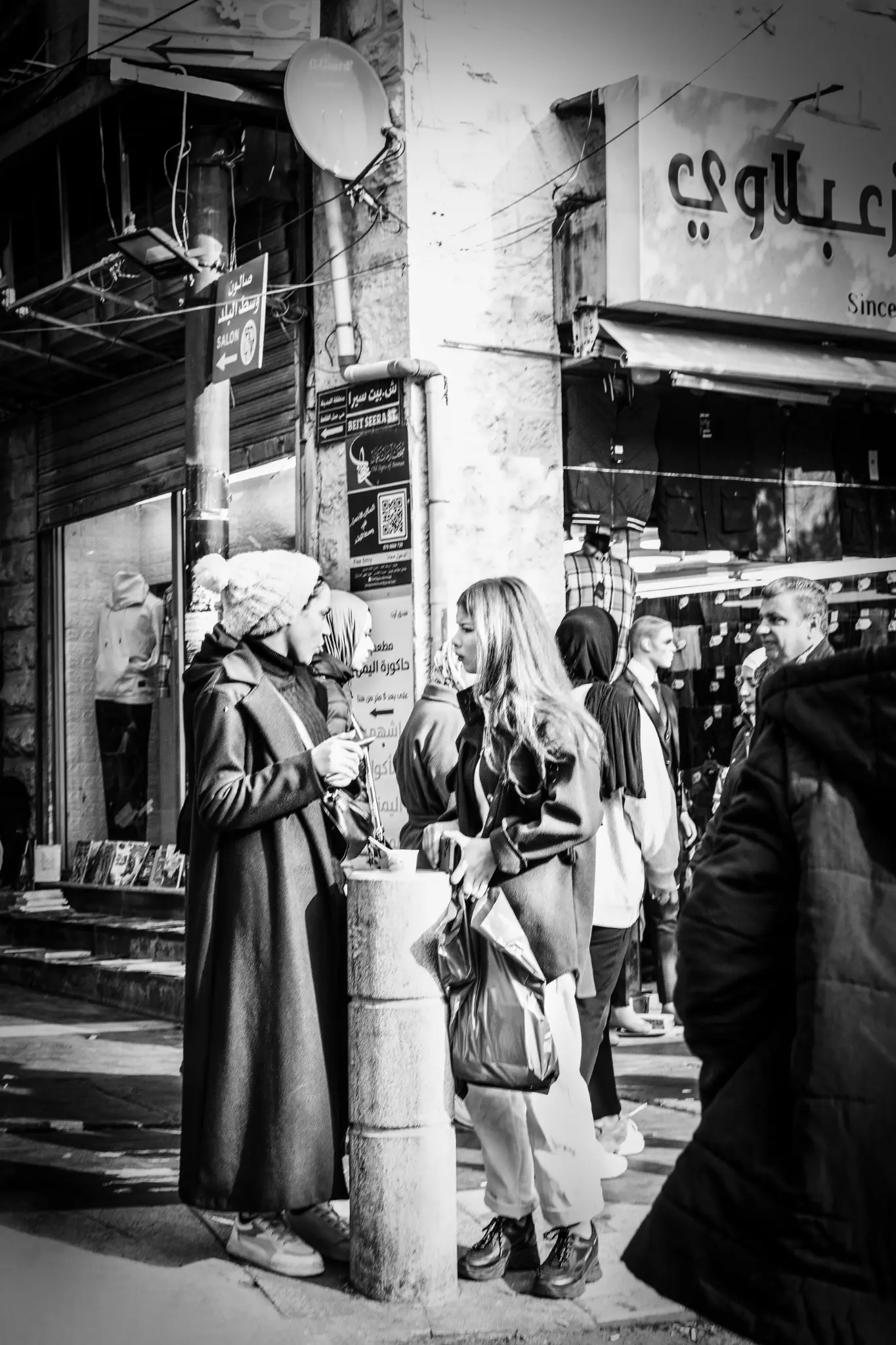 Two young women talk on a crowded street in Amman.