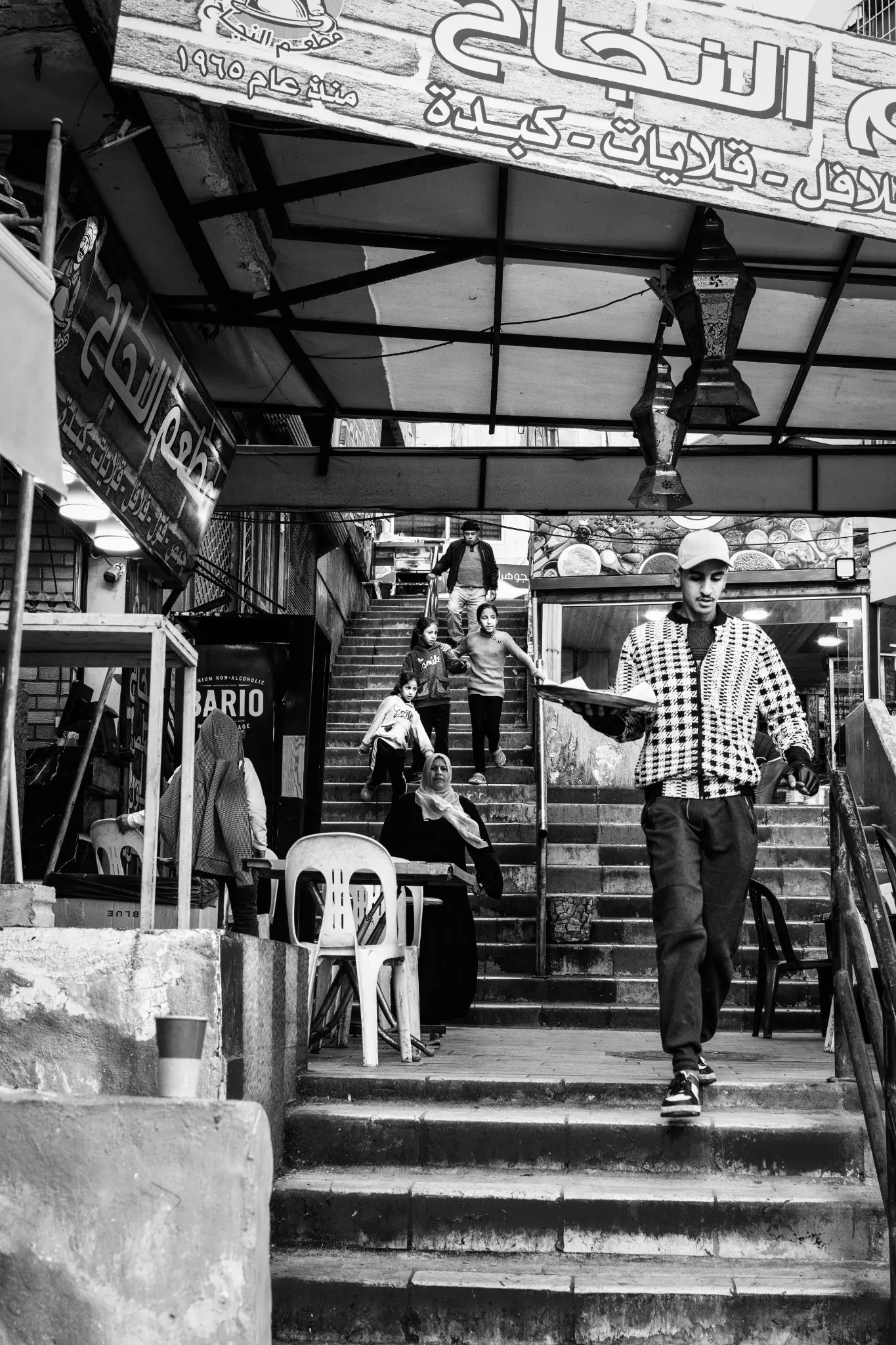 A young waiter and a family descend the steps of an Amman market.