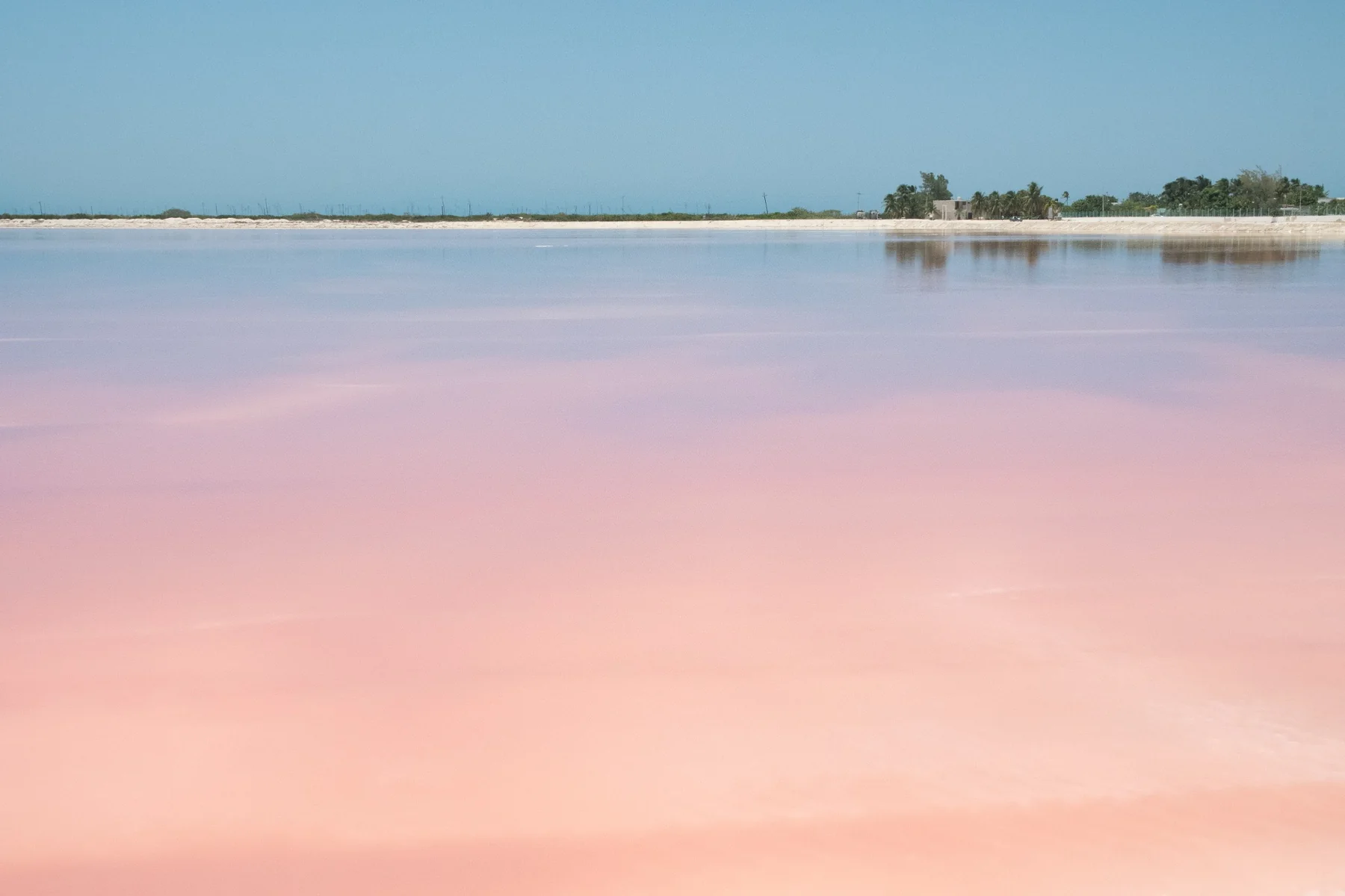 A pale pink lagoon beneath a clear sky.
