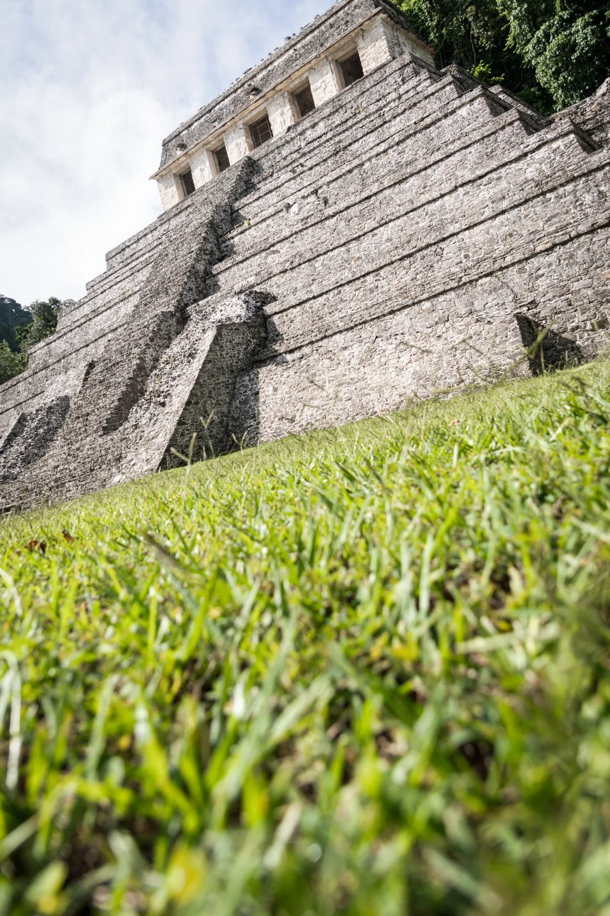 A Maya pyramid photographed from below with grass in the foreground.