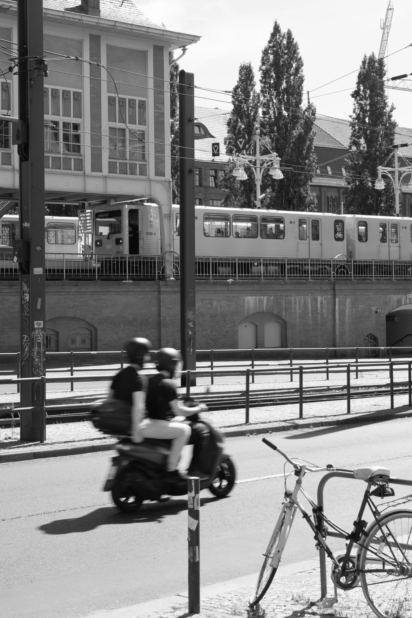 Un treno passa sopra la strada mentre uno scooter sfocato attraversa il primo piano
