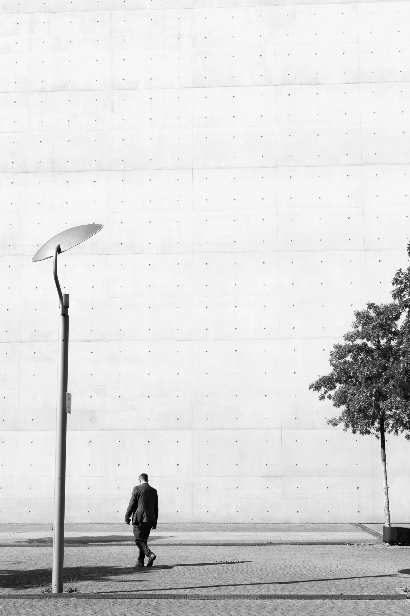 Un uomo cammina davanti a un grande muro bianco