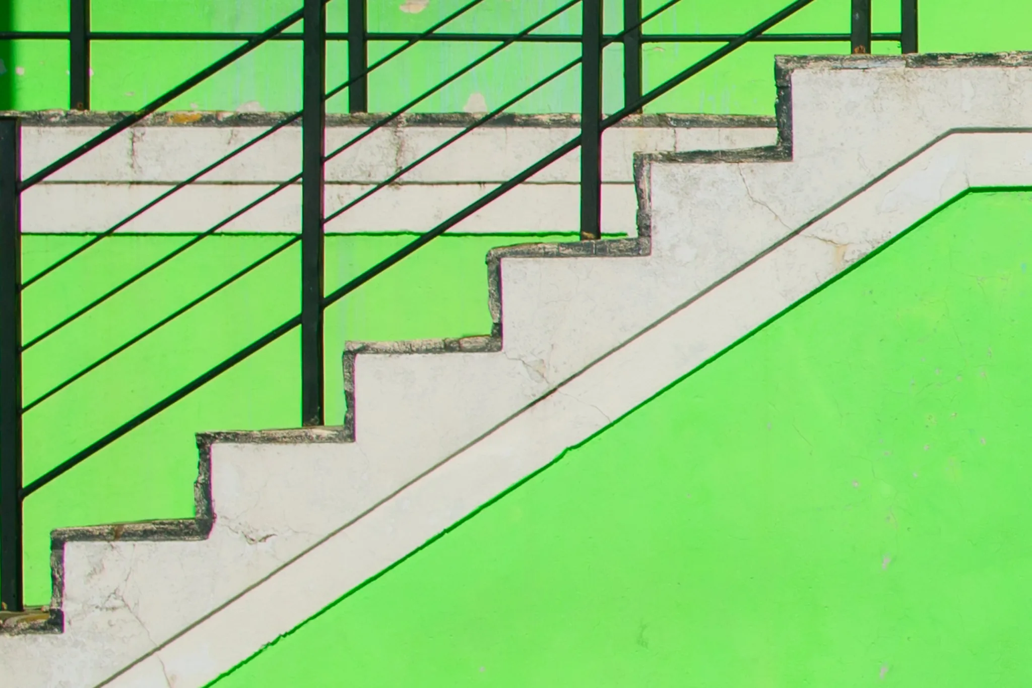 A white staircase and black railings on a bright green wall. A white staircase and black railings on a bright green wall.