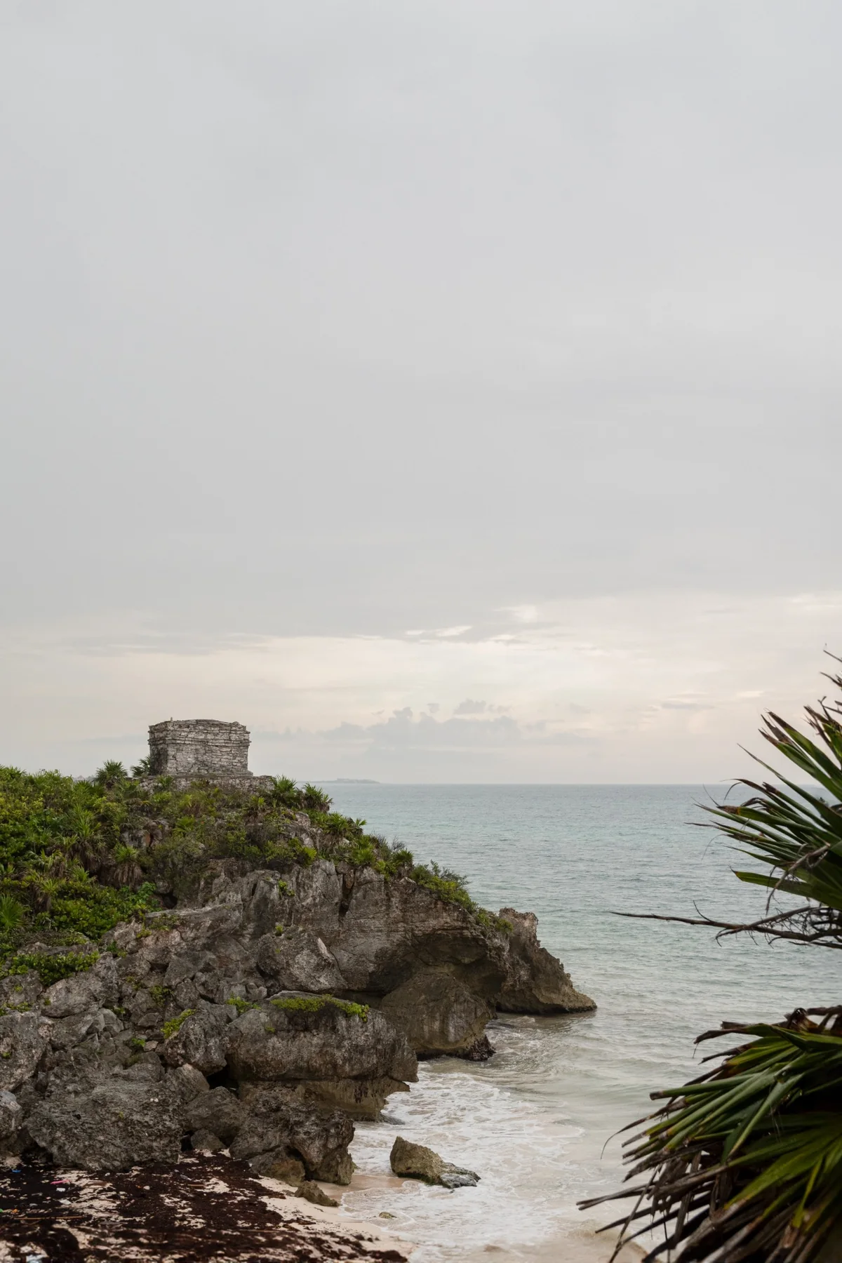 The cliffs of Tulum, with the sea and a temple in the distance.
