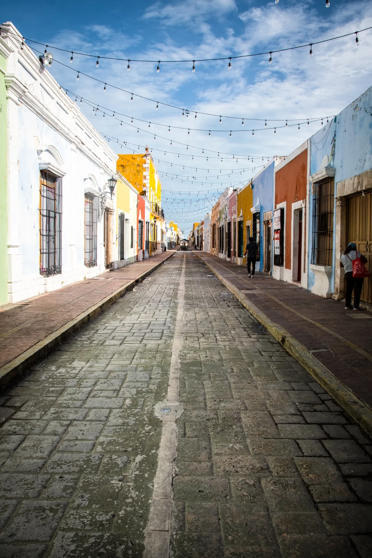 A colourful street with strings of lights suspended across the historic centre.